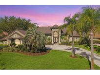 Stunning home features a circular driveway, well-manicured lawn, and beautiful landscaping, including mature palm trees at 5384 Mira Vista Dr, Palm Harbor, FL 34685