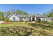 Charming one-story home with a lush green lawn, landscaped garden beds, and a welcoming entrance at 6644 Par Ct, Wesley Chapel, FL 33544