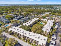 Expansive aerial view of community featuring mature trees, several condo buildings and community pool at 11700 Park Blvd # 202, Seminole, FL 33772