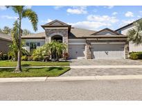 Charming single-story home featuring a stone facade, three-car garage, and beautifully landscaped front yard at 13227 Wildflower Meadow Dr, Riverview, FL 33579