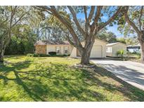 Charming single-story home featuring stone accents, a well-manicured lawn, and mature shade trees at 2258 Waterfall Dr, Spring Hill, FL 34608