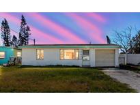 Charming single-story home with a well-maintained lawn and attached garage under a vivid sunset at 596 S Bayshore Dr, Madeira Beach, FL 33708