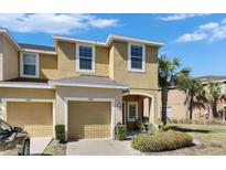 Inviting exterior of a two-story townhome featuring a private garage, lush landscaping and a sunny sky at 6907 Holly Heath Dr, Riverview, FL 33578