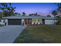 Charming single-story home featuring a well-manicured lawn, two-car garage, and striking red front door at 7040 Dr Martin Luther King Jr S St, St Petersburg, FL 33705