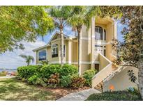 Beautiful two-story tan home with lush landscaping and a view of the water at 104 Westbrook Ct, Safety Harbor, FL 34695
