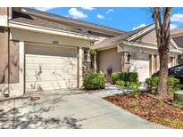 Attached garages with tan doors in a two-story townhome with well-maintained landscaping at 11190 Windsor Place Cir, Tampa, FL 33626