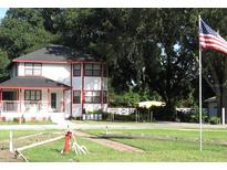Charming two-story home with a red trimmed exterior, a front porch and American flag on a spacious lot at 11326 Brightridge Dr, Seffner, FL 33584