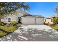 Charming single-story home with a three-car garage, well-manicured lawn, and lovely landscaping under a bright blue sky at 12513 30Th Street E Cir, Parrish, FL 34219