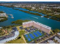 Beautiful aerial view of a large condo building near a bay and tennis courts on a sunny day at 19451 Gulf Blvd # 301, Indian Shores, FL 33785