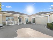 Beige single-story home with a driveway, two-car garage, and a front porch with white railings at 2325 W Del Webb Blvd, Sun City Center, FL 33573