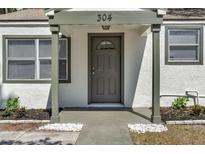Charming front entrance with well-maintained landscaping, a gray front door, and classic architectural details at 304 E Hanlon St, Tampa, FL 33604