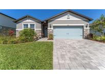 Charming single-story home featuring a well-manicured lawn, stone accents, and a light blue garage door at 34311 Evergreen Hill Ct, Wesley Chapel, FL 33545