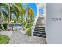 Beautiful entryway with gray pavers leading to stairs, palm trees, and a glimpse of the community pool at 7014 Grevilla S Ave, South Pasadena, FL 33707