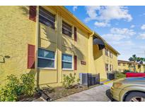Condo with yellow siding, dark red shutters, and a well-kept lawn on a sunny day at 7512 Dolonita Dr # 7512, Tampa, FL 33615