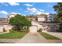 Charming townhome with a two-car garage, terracotta roof, and lush landscaping in a desirable community at 891 Lantern Way # 13-103, Clearwater, FL 33765