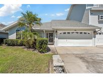 Charming single-story home featuring a two-car garage, lush landscaping, and mature palm trees at 11722 Currie Ln # B3, Largo, FL 33774