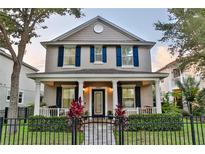 Charming two-story home featuring a welcoming front porch with decorative columns and a black metal fence at 16918 Dorman Rd, Lithia, FL 33547