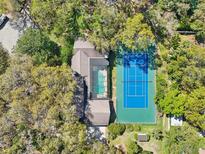 Aerial view of a luxurious home with a pool and tennis court surrounded by lush greenery at 2112 Laurence Dr, Clearwater, FL 33764