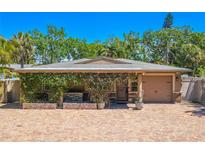Charming single-story home featuring a brick driveway, lush greenery, and a cozy front porch at 2121 Park N St, St Petersburg, FL 33710