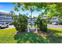 Beautifully landscaped entrance to condo complex with decorative statues and mature trees at 2401 Ecuadorian Way # 57, Clearwater, FL 33763