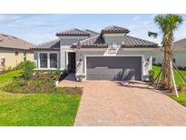 Charming single-story home with a tile roof, brick driveway, and well-maintained landscaping at 4574 Freccia Loop, Wesley Chapel, FL 33543
