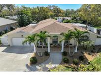 Beautiful home featuring a well-manicured lawn, mature palm trees, and a charming front porch at 609 Osceola Rd, Belleair, FL 33756