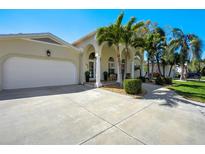 Beautiful home with white columns, arched entryway, attached garage, and a driveway surrounded by palm trees and landscaping at 609 Osceola Rd, Belleair, FL 33756