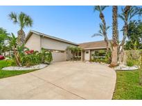 Well-maintained single-story house boasts a large curved driveway, palm trees, and a neatly kept front lawn at 6109 Schooner Way, Tampa, FL 33615