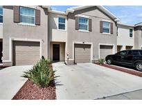 Beige two-story townhouse featuring a one car garage, front door, rock landscaping and a well maintained lawn at 708 Barclay Wood Dr, Ruskin, FL 33570