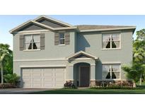 Charming two-story home featuring a stucco facade, attached garage and well-manicured lawn at 7756 Wheat Stone Dr, Zephyrhills, FL 33540