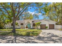 Charming home featuring a two-car garage, manicured lawn, mature trees, and a welcoming entryway at 8236 36Th N Ave, St Petersburg, FL 33710