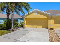 A sunlit, yellow garage door on a charming home with a well-maintained driveway and lush landscaping at 11422 Captiva Kay Dr, Riverview, FL 33569