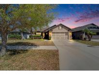 Inviting home featuring a two-car garage, stone accents, and manicured landscaping at dusk at 12220 Legacy Bright St, Riverview, FL 33578