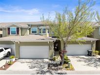 Townhouse with two-car garage, neutral stucco, well-manicured landscaping, and mature shade tree at 12919 Whittington Ct, Largo, FL 33773