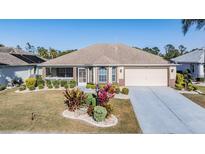Charming single-story home features a manicured lawn, mature landscaping, and a two-car garage at 2335 E Del Webb Blvd, Sun City Center, FL 33573