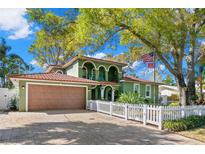 Charming two-story home boasts mature trees, a two-car garage, a quaint white picket fence, and an American flag at 550 7Th S St, Safety Harbor, FL 34695
