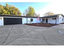 Charming single-story home features an attached two-car garage, a manicured lawn and an American flag at 9308 Pinero St, Spring Hill, FL 34608