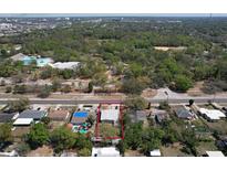 An aerial view shows the property with a tree filled landscape and nearby community pool at 10928 N 15Th St, Tampa, FL 33612
