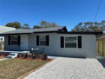 Charming single-story home featuring gray stucco, black shutters, and a gravel driveway at 1913 Park Ave, Tarpon Springs, FL 34689