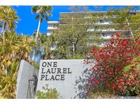 View of the condo building with lush landscaping and a vibrant red flowering bush in front at 201 W Laurel St # 212, Tampa, FL 33602