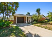 Charming single-story home with a brick facade and a driveway leading to a garage at 8706 Tahiti Ln, Tampa, FL 33615