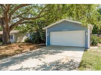 Charming home featuring an attached two-car garage and a driveway, all under the shade of mature trees at 1721 Sutton Pl, Dunedin, FL 34698