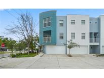 Modern townhome with a light teal and white exterior, featuring a two-car garage and manicured landscaping at 3405 W Swann Ave # 9, Tampa, FL 33609