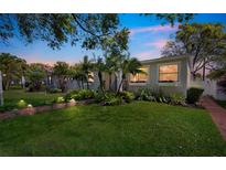 Inviting home exterior with lush lawn, garden, palm trees, and walkway lighting at 1235 14Th N St, St Petersburg, FL 33705