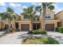 Inviting townhome exterior with a two-car garage, palm trees, and manicured landscaping, offering curb appeal and a welcoming ambiance at 2011 Hawks View Dr, Ruskin, FL 33570