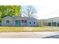 Charming single-story home with a light gray exterior, bright blue door, and covered parking at 3710 W Griflow St, Tampa, FL 33629