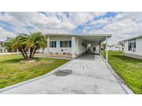 Charming mobile home featuring a covered carport and well-maintained front yard with a palm tree at 4618 Newcomb Ave, Zephyrhills, FL 33541