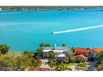 Waterfront home with a private drive surrounded by lush landscaping, palm trees, and stunning bay views at 520 Belle Isle Ave, Belleair Beach, FL 33786
