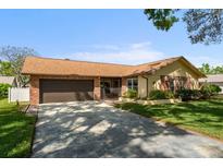 Charming single-story home featuring a brick facade, attached two-car garage, and well-maintained lawn at 2958 Macalpin N Dr, Palm Harbor, FL 34684