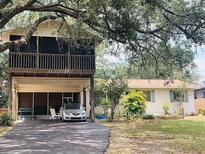 Charming multi-level home featuring a covered parking area, screened in porch, and mature landscaping at 4904 E River Hills Dr, Tampa, FL 33617